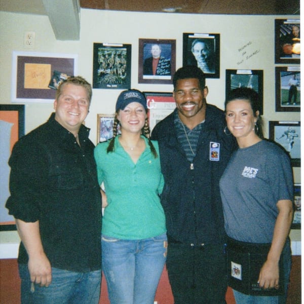 Four smiling people, including Herschel Walker, pose at Doe's Eat Place.