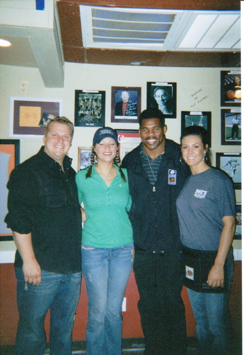 Four smiling people, including Herschel Walker, pose at Doe's Eat Place.