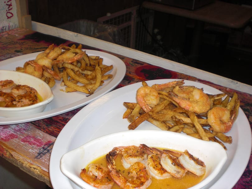 Two plates of fried shrimp and french fries, with a small dish of shrimp in sauce.