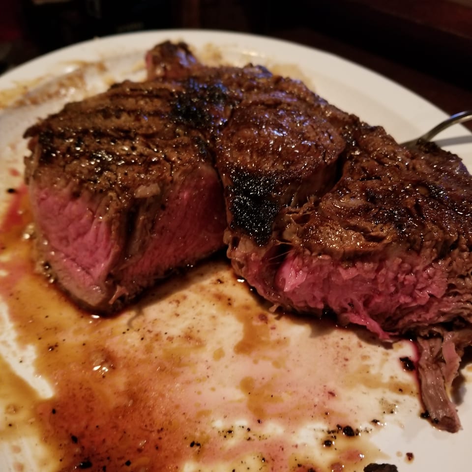 A perfectly cooked steak, medium-rare, sliced open on a white plate with juices.