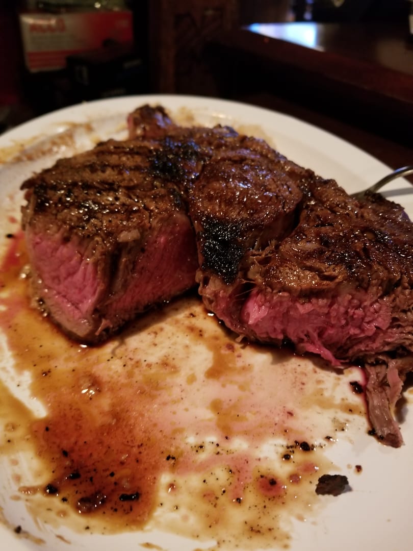 A perfectly cooked steak, medium-rare, sliced open on a white plate with juices.